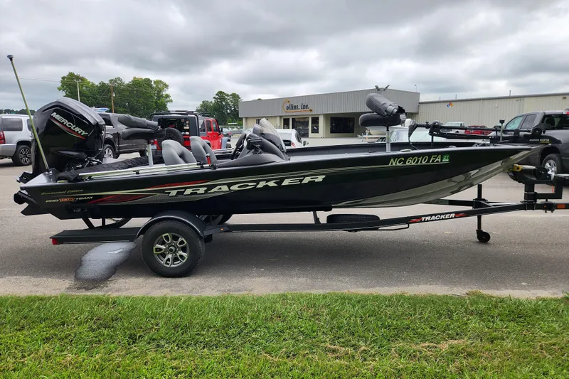 Slide: The Image of 2023 Tracker Pro Team 190 TX boat on trailer, parked outdoors near industrial buildings. - 5