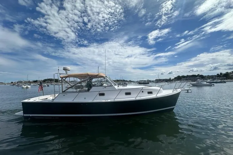 The Image of 2002 Mainship Pilot 34 boat on calm water under a partly cloudy sky. - 0