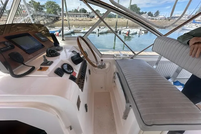 Slide: The Image of 2002 Mainship Pilot 34 helm with steering wheel, navigation instruments, and cushioned seating. - 14