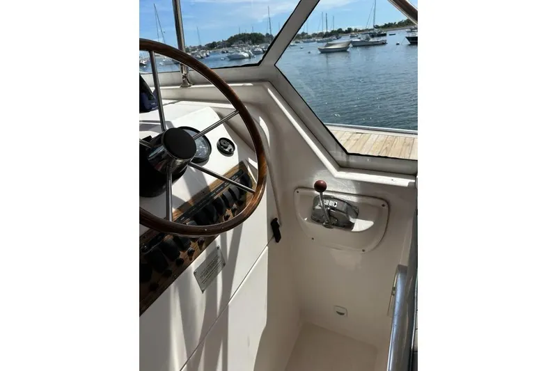 Slide: The Image of 2002 Mainship Pilot 34 helm with wooden steering wheel, overlooking marina. - 15