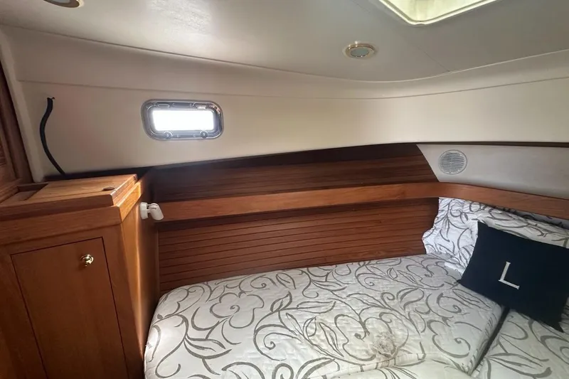 Slide: The Image of Cozy cabin interior of 2002 Mainship Pilot 34 with wood accents and patterned bedding. - 24