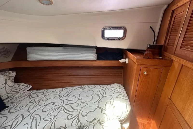 Slide: The Image of Cozy cabin interior of 2002 Mainship Pilot 34 with wood paneling and patterned bedding. - 25