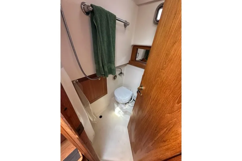 Slide: The Image of Compact bathroom in 2002 Mainship Pilot 34 boat with wooden door and towel rack. - 27