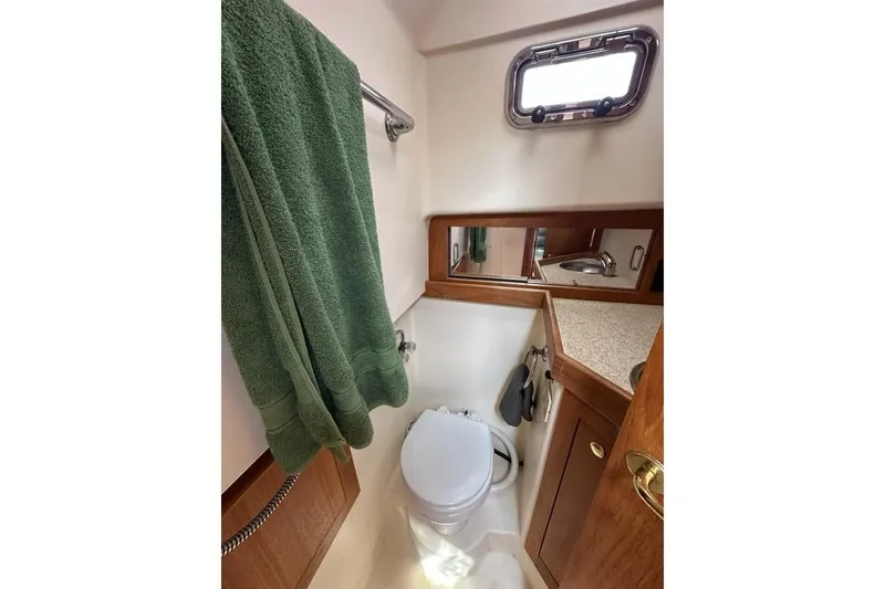 Slide: The Image of 2002 Mainship Pilot 34 bathroom with toilet, green towel, and countertop. - 28