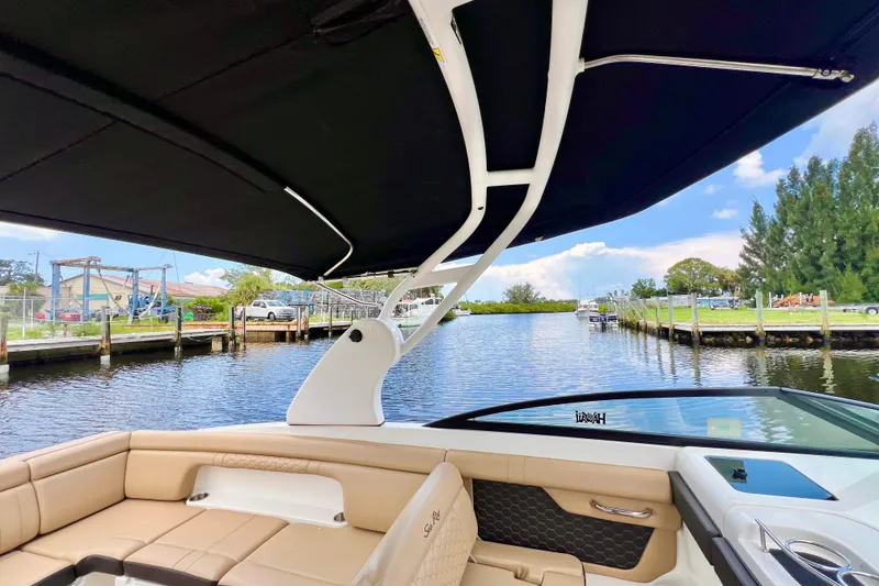 Slide: The Image of 2019 Sea Ray SDX 290 Outboard boat interior with canopy, docked by a scenic waterway. - 14