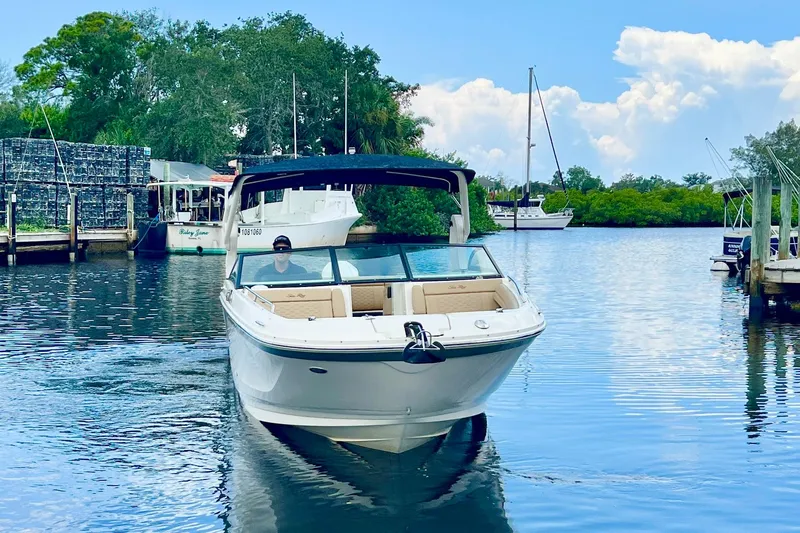 Slide: The Image of 2019 Sea Ray SDX 290 Outboard cruising on a calm river with lush greenery. - 2