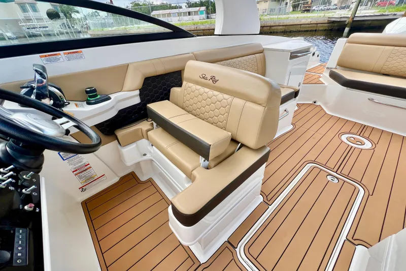 Slide: The Image of 2019 Sea Ray SDX 290 Outboard interior with tan seating and wood-style flooring. - 24