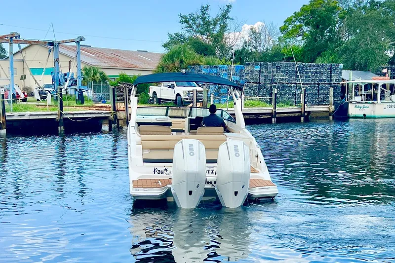 Slide: The Image of 2019 Sea Ray SDX 290 Outboard cruising on a calm waterway near a dock. - 6