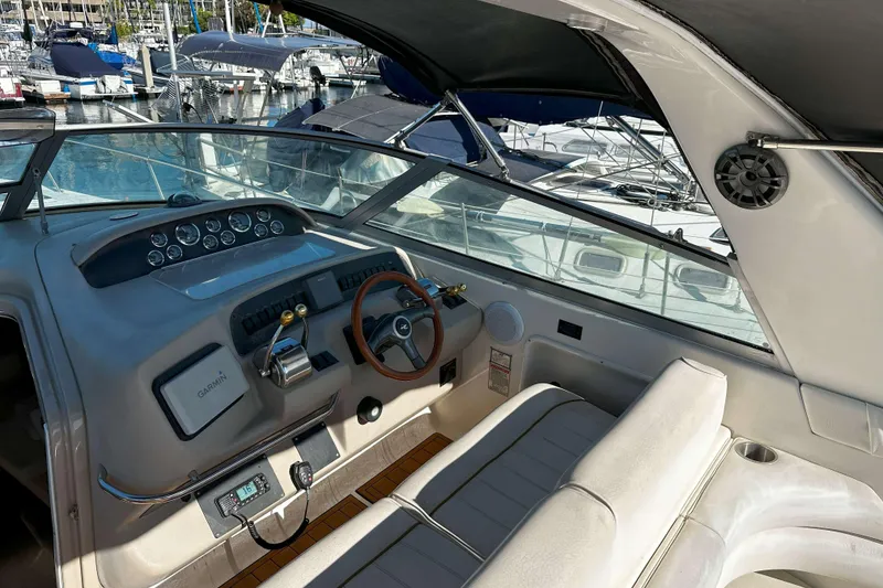 Slide: The Image of 1999 Sea Ray 330 Sundancer cockpit with steering wheel, controls, and marina view. - 1