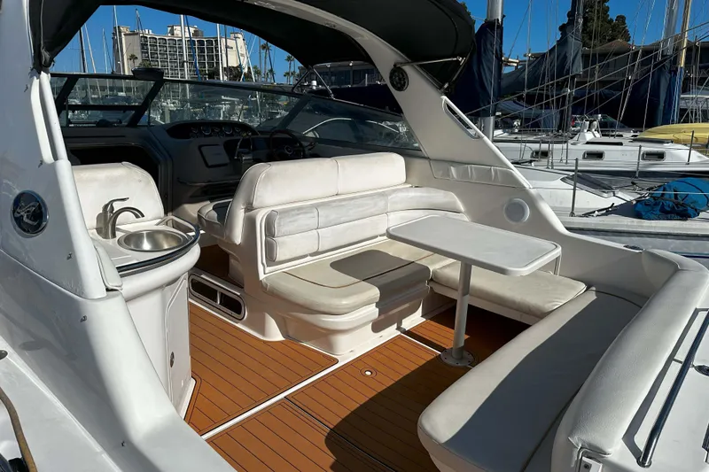 Slide: The Image of 1999 Sea Ray 330 Sundancer interior with seating, table, and sink, docked at marina. - 13