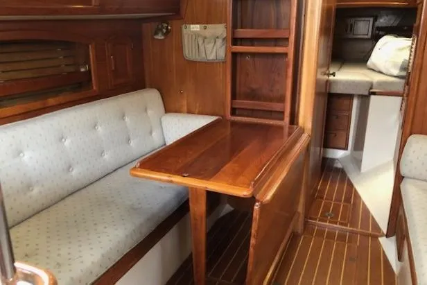 Slide: The Image of Interior of 1988 Pacific Seacraft 34 sailboat with wooden table and cushioned seating. - 13