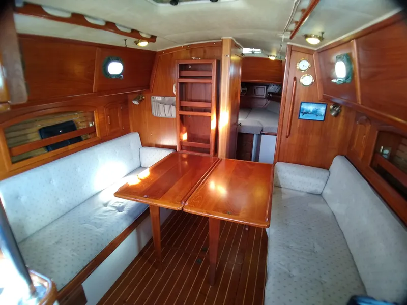Slide: The Image of Interior of 1988 Pacific Seacraft 34 sailboat with wooden table and cushioned seating. - 14