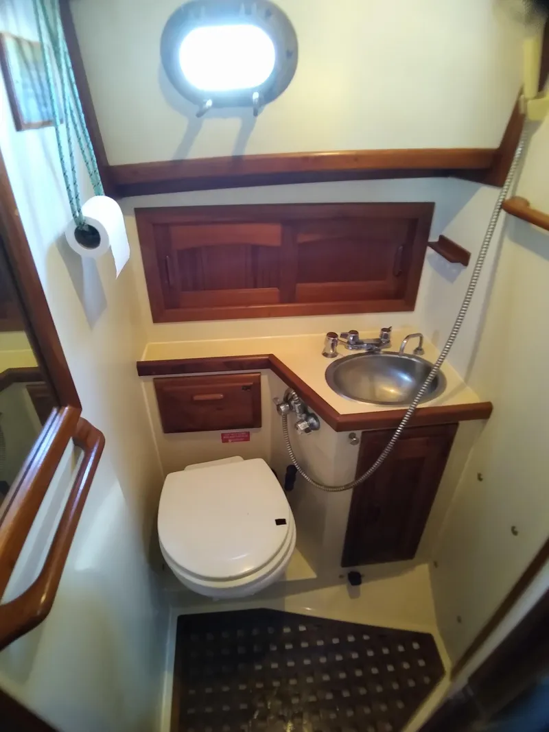 Slide: The Image of 1988 Pacific Seacraft 34 yacht bathroom with wooden cabinetry, sink, and toilet. - 17