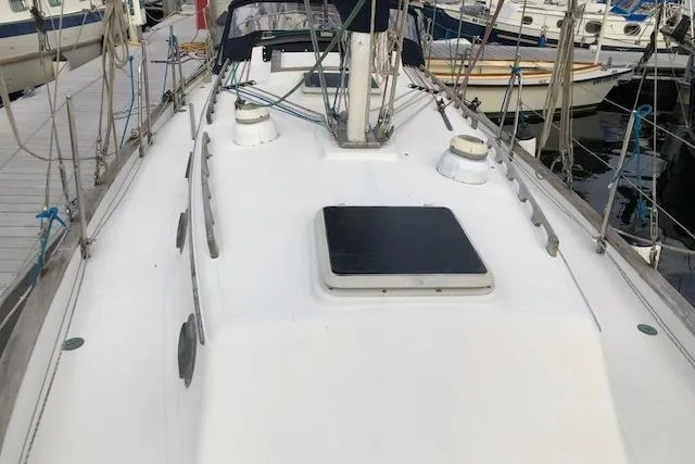 Slide: The Image of 1988 Pacific Seacraft 34 sailboat deck view at marina, showcasing rigging and hatch. - 4