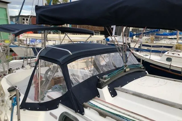 Slide: The Image of 1988 Pacific Seacraft 34 sailboat with navy canvas cover in marina setting. - 6