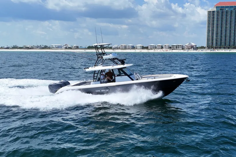 The Image of 2024 Everglades 395 Center Console boat cruising on ocean near beachfront buildings. - 0