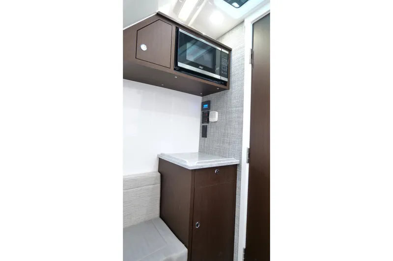 Slide: The Image of Compact interior of 2024 Everglades 395 Center Console with microwave and cabinetry. - 59