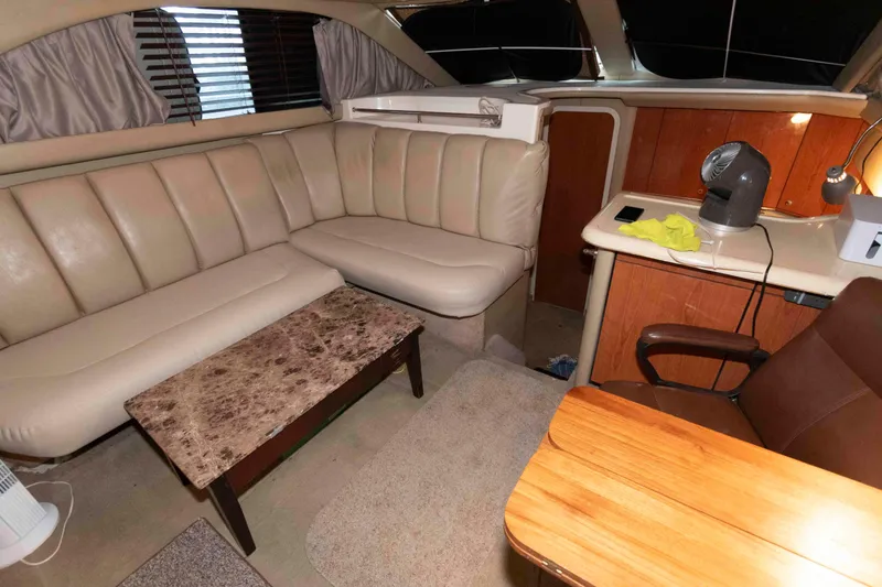 Slide: The Image of 1998 Sea Ray 370 Aft Cabin interior with beige seating, table, and desk area. - 12