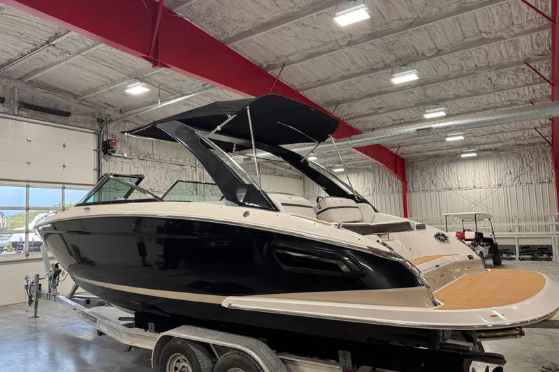 Slide: The Image of 2015 Regal 2800 Bowrider boat in indoor storage, black hull, on trailer. - 4