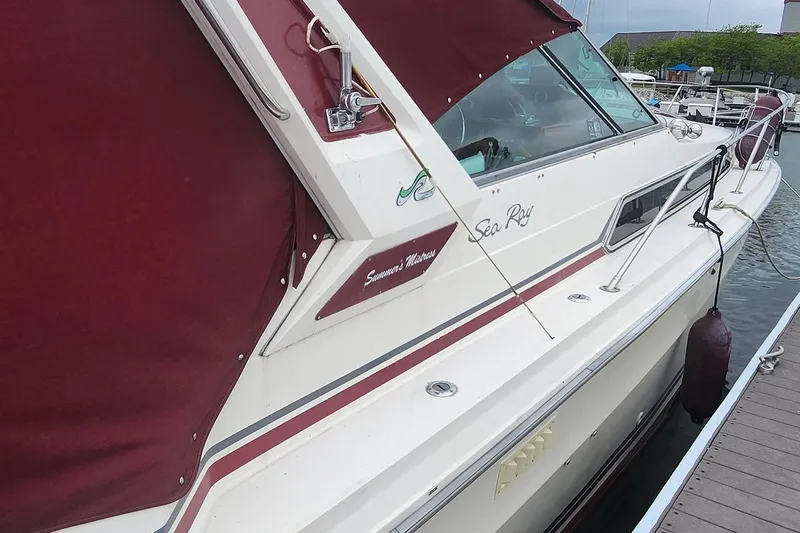 Slide: The Image of 1987 Sea Ray 340 Sundancer docked, featuring maroon canvas cover and sleek design. - 16