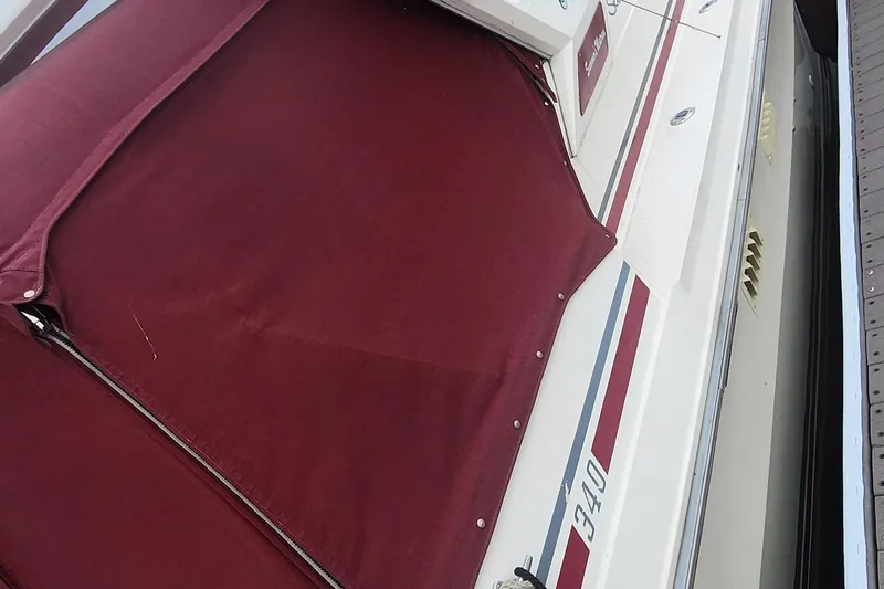 Slide: The Image of 1987 Sea Ray 340 Sundancer boat with maroon cover and striped detailing. - 17