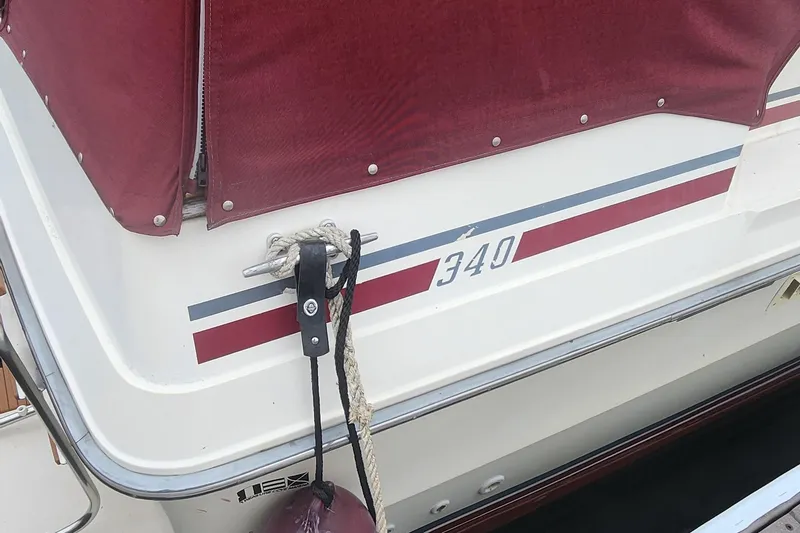 Slide: The Image of 1987 Sea Ray 340 Sundancer boat with maroon cover and docked rope. - 18