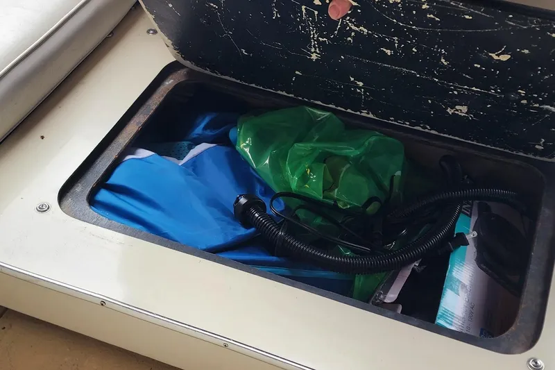 Slide: The Image of Storage compartment on a 1987 Sea Ray 340 Sundancer boat with various items inside. - 29