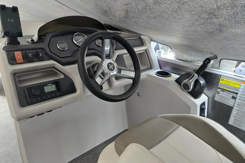 Slide: The Image of 2023 Godfrey Sweetwater 2086 CX boat dashboard with steering wheel and controls. - 2