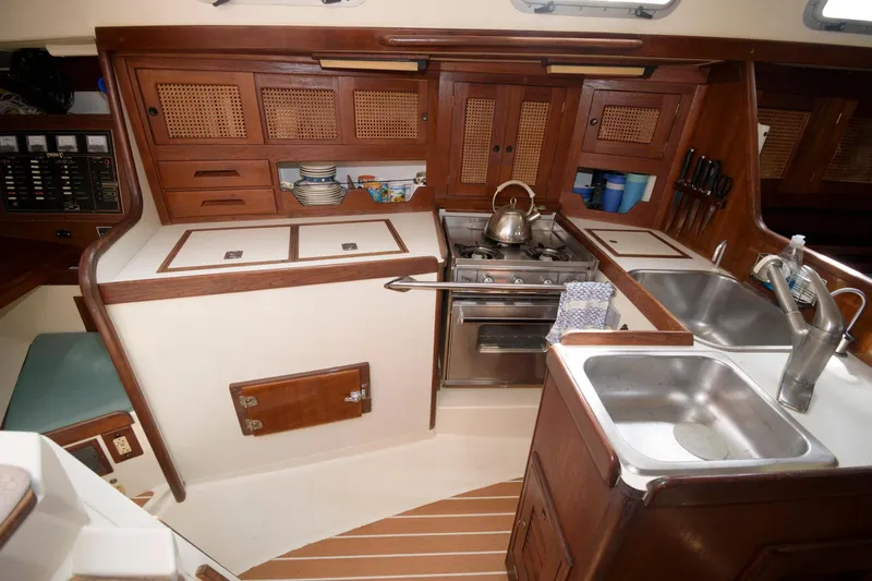 Slide: The Image of 1985 Tartan 40 yacht kitchen with stove, sink, and wooden cabinets. - 15