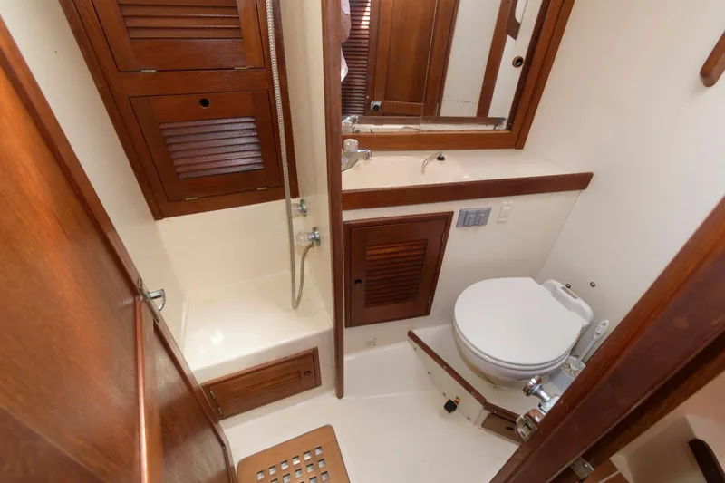 Slide: The Image of 1985 Tartan 40 yacht bathroom with wooden cabinets, shower, and toilet. - 24