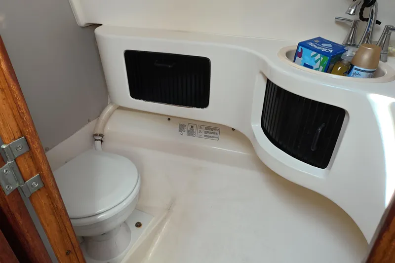 Slide: The Image of 1992 Luhrs 300 Tournament boat bathroom with toilet, sink, and storage compartments. - 11