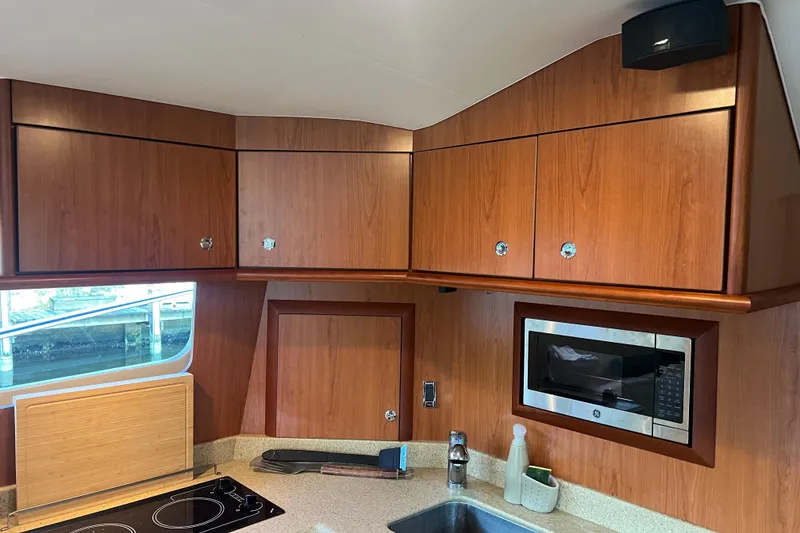 Slide: The Image of 2008 Luhrs 35 Convertible yacht kitchen with wooden cabinets, microwave, and stovetop. - 49