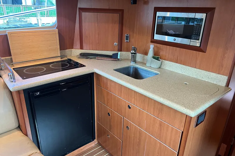 Slide: The Image of 2008 Luhrs 35 Convertible yacht kitchen with stove, sink, microwave, and compact fridge. - 50