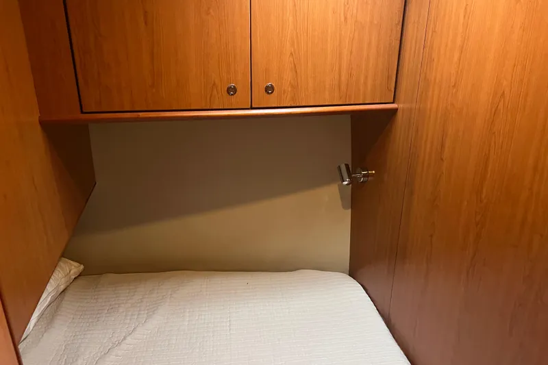 Slide: The Image of 2008 Luhrs 35 Convertible cabin interior with wooden cabinets and a cozy bed. - 56