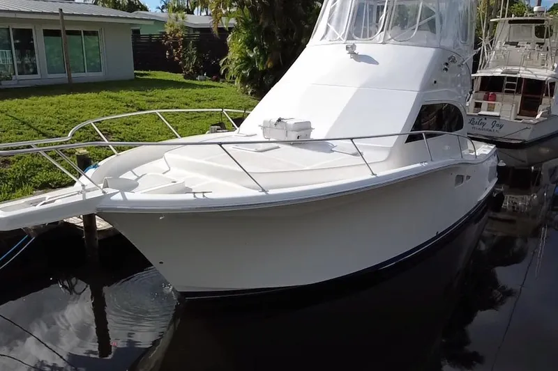 Slide: The Image of 2008 Luhrs 35 Convertible yacht docked near lush greenery. - 6