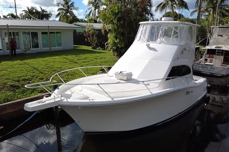 Slide: The Image of 2008 Luhrs 35 Convertible boat docked near a house with palm trees. - 8