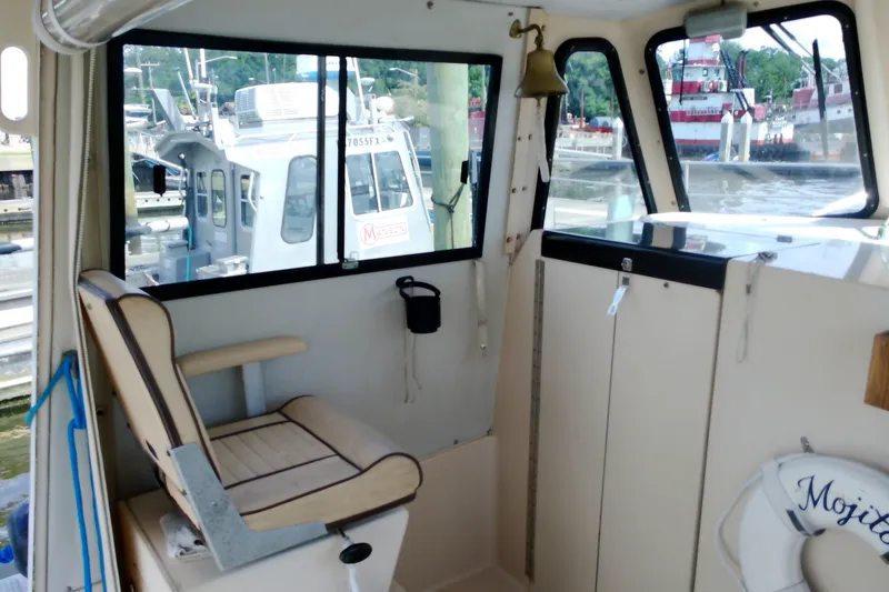 Slide: The Image of Interior of 2000 Atlas Boat Works Acadia 25, featuring seating and windows with marina view. - 10