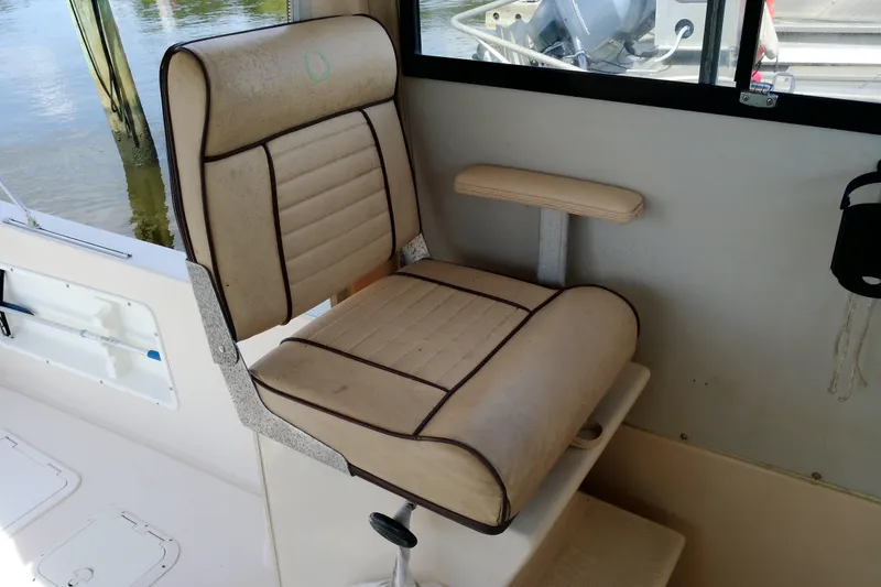 Slide: The Image of Captain's chair on 2000 Atlas Boat Works Acadia 25, featuring beige upholstery and armrest. - 28