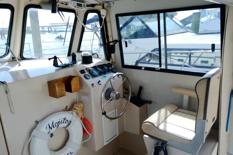 Slide: The Image of Interior of 2000 Atlas Boat Works Acadia 25, featuring helm and seating area. - 32