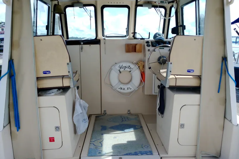 Slide: The Image of Interior of 2000 Atlas Boat Works Acadia 25, featuring helm and seating area. - 35