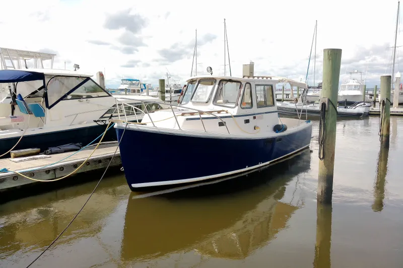 Slide: The Image of 2000 Atlas Boat Works Acadia 25 docked at a marina, featuring a classic blue hull. - 4