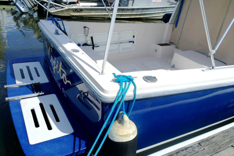 Slide: The Image of Atlas Boat Works Acadia 25, 2000 model, docked with blue hull and white deck. - 6