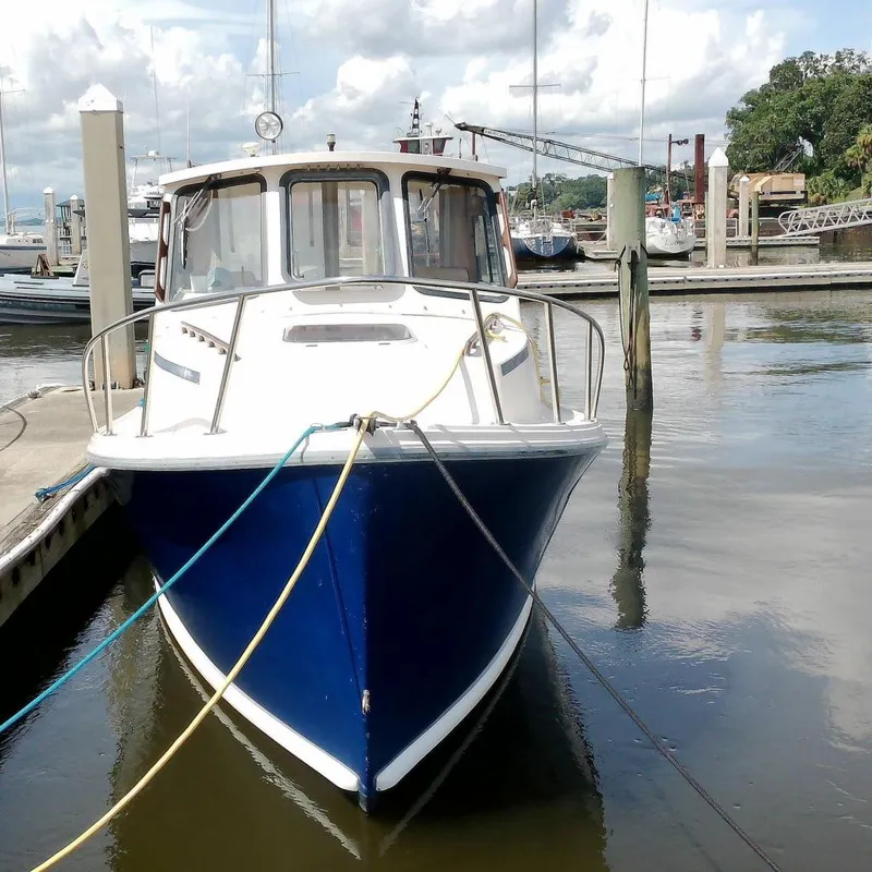 Slide: The Image of 2000 Atlas Boat Works Acadia 25 docked at a marina under a cloudy sky. - 1
