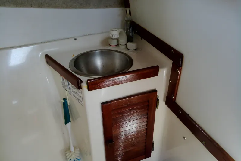 Slide: The Image of 2000 Atlas Boat Works Acadia 25 interior sink with wooden accents and storage cabinet. - 14