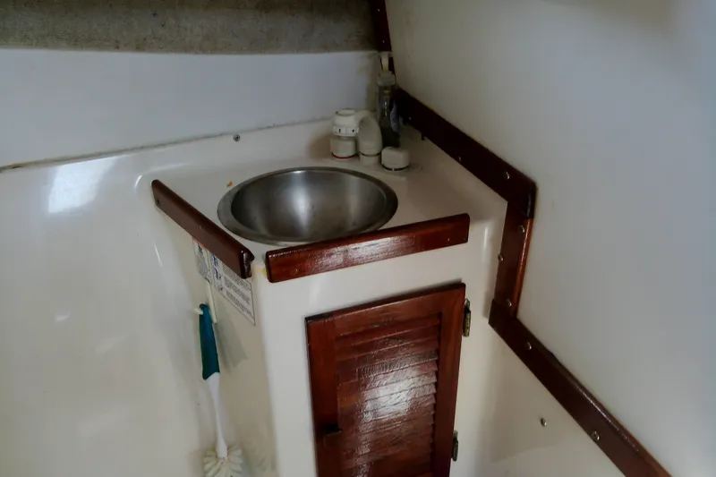 Slide: The Image of Interior of 2000 Atlas Boat Works Acadia 25, featuring a compact sink and wooden cabinetry. - 15