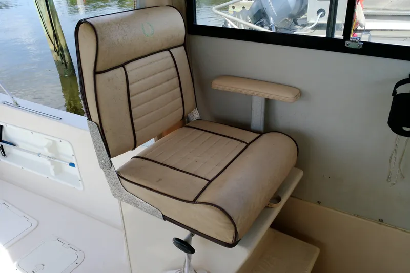 Slide: The Image of Captain's chair on 2000 Atlas Boat Works Acadia 25, featuring beige upholstery and armrest. - 27