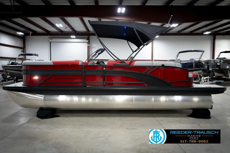 Slide: The Image of 2026 Bennington 22 SLJ pontoon boat in showroom, featuring sleek red design and canopy. - 10