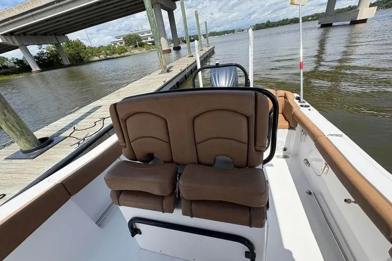 Slide: The Image of 2021 Seahunt 255 Ultra boat interior with brown seating, docked by a bridge. - 8