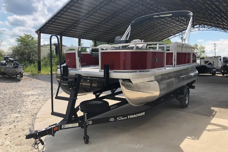 Slide: The Image of 2026 Sun Tracker Bass Buggy 18 DLX pontoon boat on trailer under shelter. - 4