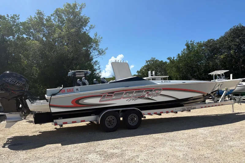 The Image of 2025 Legend race boat on trailer, for sale, parked outdoors under clear sky. - 1